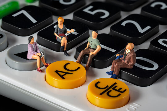 Miniature 4 people sitting on a white calculator. meeting or discussion using as business concept. Macro