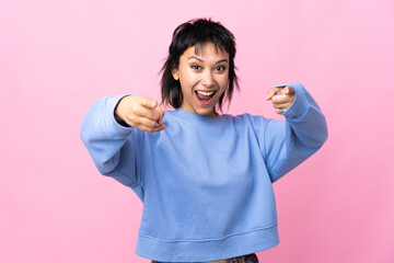 Young Uruguayan woman over isolated pink background surprised and pointing front