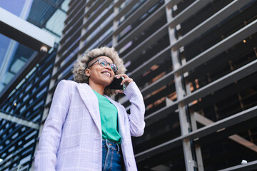 Confident cool black business woman talking on the phone outside a modern building. Young female...