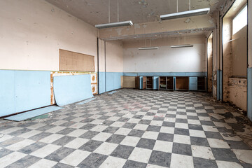 Public accessible abandoned room with open cabinet in blue tones and chessboard patterned floor