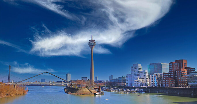 Düsseldorf (Medienhafen), Germany - March 9. 2022: Panoramic view over river rhine on skyline with tower, gehry houses, bridge against spectacular blue winter sky