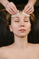 Naklejka premium Pleased woman receiving forehead massage in a beauty salon
