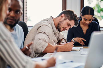 The best time to take notes. Cropped shot of a handsome young businessman taking notes during a meeting in the boardroom.