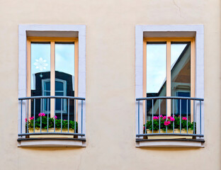 Fototapeta na wymiar Two french style balcony windows with violet colored geranium flower pots, house facade detail, Saxony, Germany