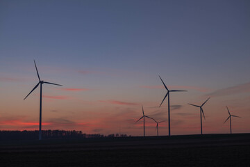 Obraz premium Wiatrowe elektrownie na tle wieczornego nieba.