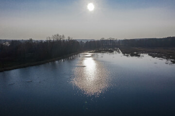Jezioro w słoneczny, wiosenny dzień widziane z dużej wysokości. Zdjęcie zrobione z użyciem latającego drona. - 492362181