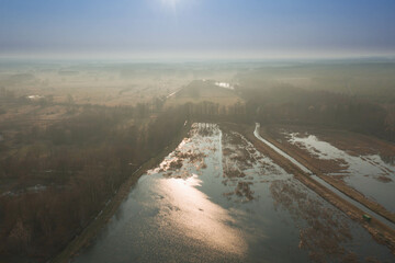 Jezioro w słoneczny, wiosenny dzień widziane z dużej wysokości. Zdjęcie zrobione z użyciem latającego drona. - 492362186