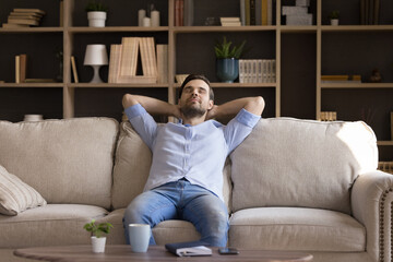 Peaceful millennial guy relax at quiet cozy living room dream enjoy tranquility peace of mind. Calm...