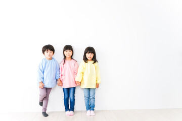 壁に並ぶ3人の幼稚園児