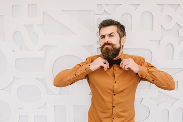 Man with a beard on a white wall background with space for text.