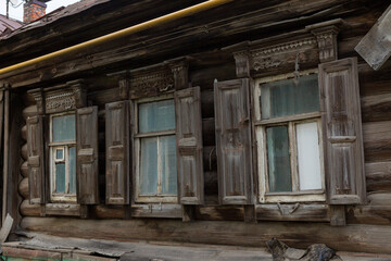 Fototapeta na wymiar The beautiful old windows with beautifully designed platbands window on an old wooden house in the city of Tula