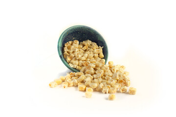 Freeze Dried Sweet Corn Spilling from Blue Pottery Bowl Isolated on White