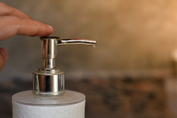 Person using hand sanitizer gel in public. Hand pressing antibacterial lotion bottle outside. Close up view of antiseptic being used in the street.