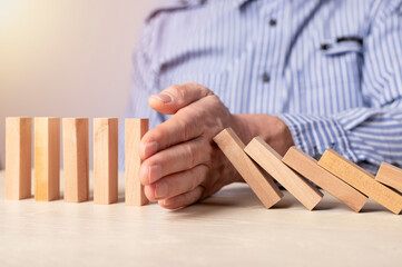Insurance concept. Businessman hand closeup protecting wood blocks from falling. Economic crisis prevention. High quality photo