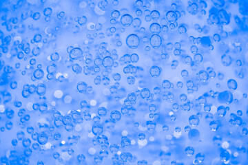 Blue transparent texture of cosmetic gel or face serum as background with bubbles and copy space. Bath cosmetic gel background. Selective focus