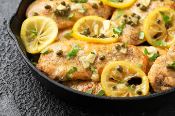 Chicken Piccata with capers, white wine sauce in iron cast pan. Italian food