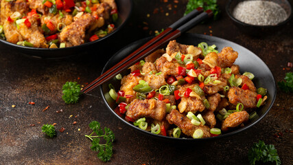 Stir fry salt and pepper pork loin with herbs in black bowl. Asian food