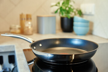 Steel frying pan in the kitchen on electric induction hob, Modern kitchen appliance - obrazy, fototapety, plakaty