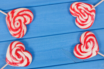 Sweet funny lollipop in shape of heart on blue boards. Surprise for child. Memory of childhood. Place for text