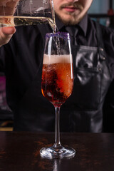 Bartender dressed in black apron and shirt make alcohol cocktail drink on black background