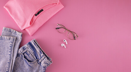 Women's clothing and accessories on a pink background, top view. Modern and casual outfit. Fashion, shopping and makeup concept.