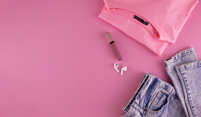 Women's clothing and accessories on a pink background, top view. Modern and casual outfit. Fashion, shopping and makeup concept.