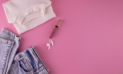 Women's clothing and accessories on a pink background, top view. Modern and casual outfit. Fashion, shopping and makeup concept.
