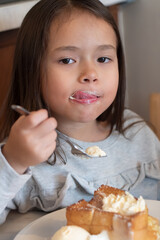Little girl eating dessert with ice cream sticking on her mouth