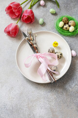 Festive Easter table setting with painted eggs, spring flowers and cutlery on light grey tabletop. Table setting for Happy Easter day. Copy space.