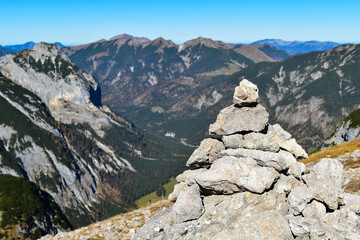 Fototapeta na wymiar Mountain view with a stacked rock pile, during a hiking trail on a sunny day. (selective focus)