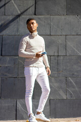 vertical portrait of Latin man with headphones and mobile on a gray wall background