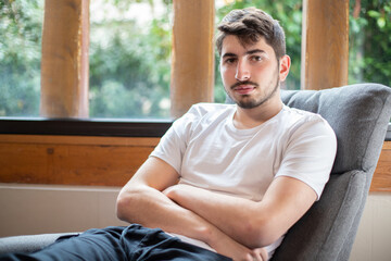 Portrait d'un jeune homme de 20 ans qui se repose dans un fauteuil à la maison.