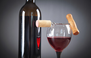 Bottle of red wine with glass and corkscrew.