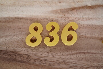 Golden Arabic numerals on a real brown and white wooden floor number 836