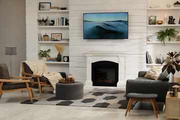 Cozy living room interior with comfortable sofa, armchairs and decorative fireplace