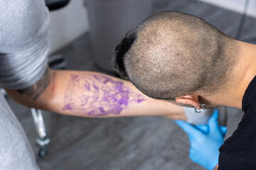 portrait of an alternative tattoo artist marking and perfecting the sketch of a tattoo on a...