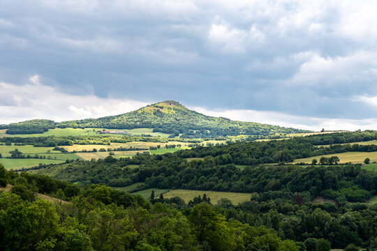 vue sur un volcan tronant au mileu d'une vall&eacute;e sur le chemin de randonn&eacute;e du puy de Lavelle dans le puy de d&ocirc;me avec ses pentes bois&eacute;es et son sommet en herbes