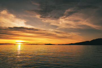 Fototapeta na wymiar Dramatic sunset over sea with clouds in the sky and mountain in background - Thailand Koh Lipe