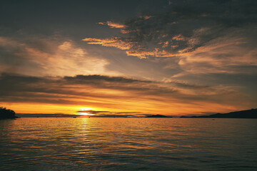 Dramatic sunset over sea with clouds in the sky and mountain in background - Thailand Koh Lipe