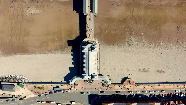 Aerial view of penarth pier flying over the peir overlooking the length of the pier and beach with tide far out.