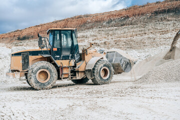 Wheel loader with large bucket on construction site or quarry. Mining heavy machinery details. Earthmoving, excavations, digging on soils.