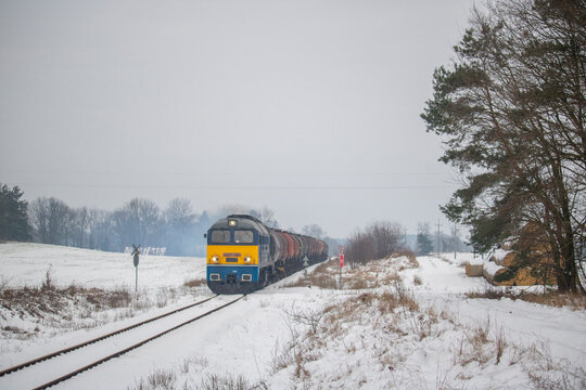 Stara lokomotywa spalinowa z pociągiem towarowym zimą