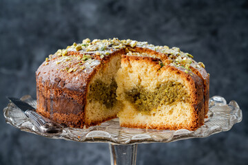 Pistachio and orange cake sprinkled with icing sugar and crushed pistachio nuts