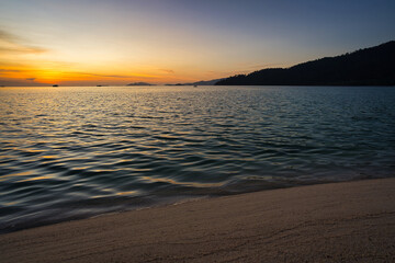 Obraz premium Sand beach with mountains and clouds during a sunset over the sea in the background - Thailand Koh Lipe