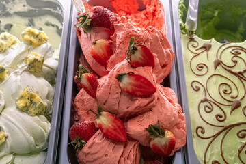 Strawberry ice cream with berries. Various ice creams in tray in the ice cream shop top view. Selective focus.