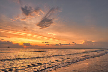 Beautiful sand beach, wonderful clouds in the sky during a dramatic sunset and a yacht on the sea with waves - Koh Lanta Thailand
