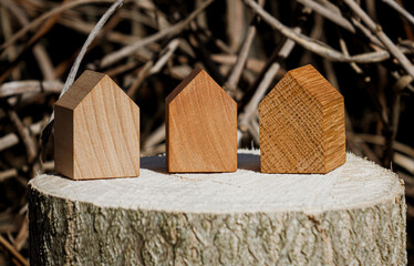 wooden house models on tree stump in the outdoors. concept image for wood as a renewable and sustainable building material for modular timber architecture. 