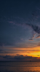 Beautiful sand beach, wonderful clouds in the sky during a dramatic sunset and a yacht on the sea with waves - Koh Lanta Thailand