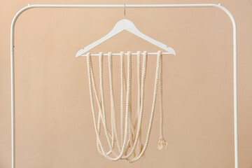 Rack with clothes hanger and rope on light background