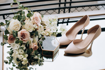 Beautiful wedding bouquet of beige and white roses and wedding shoes